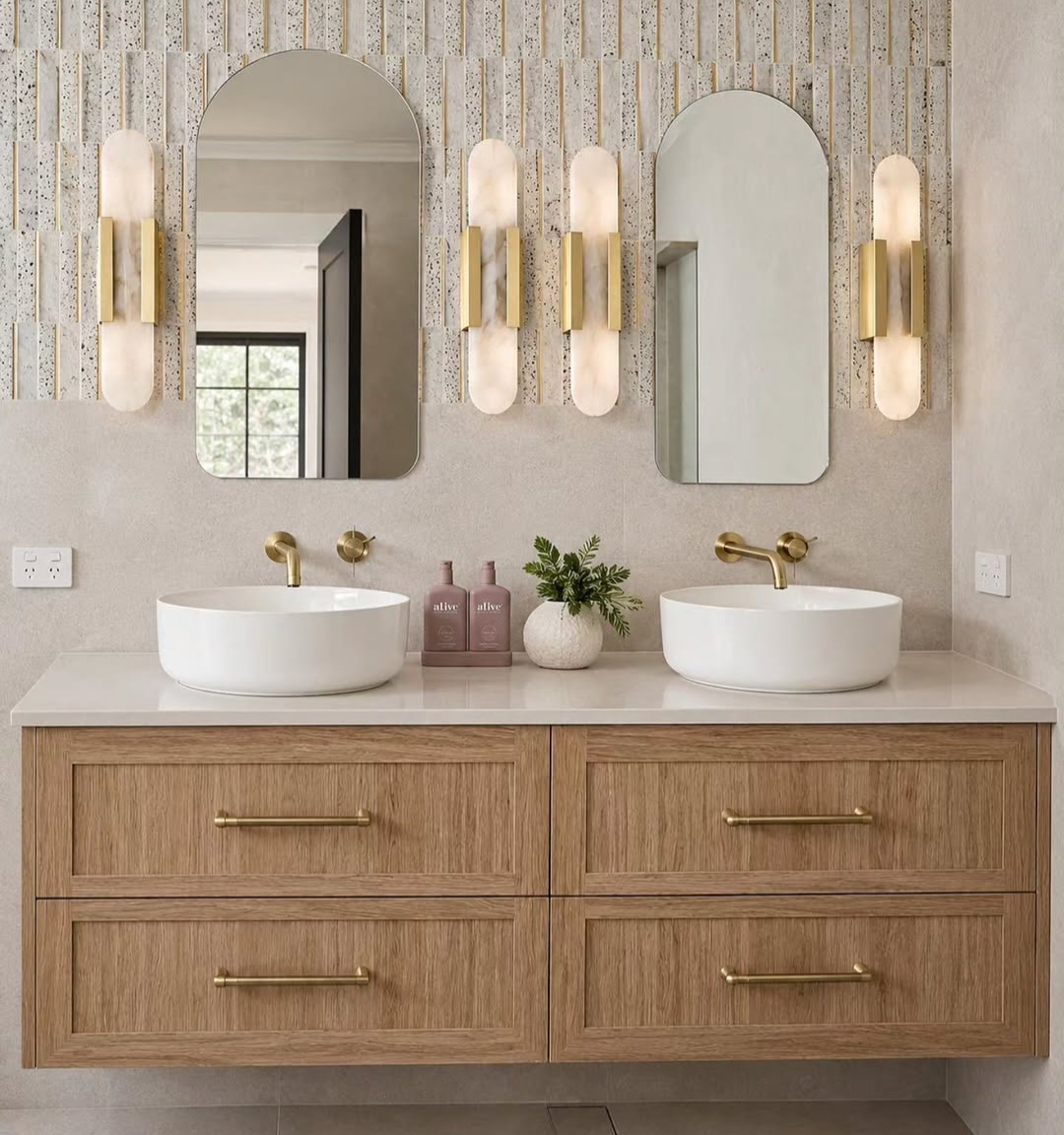 Double vanity ensuite with arched mirrors and warm brass wall lighting