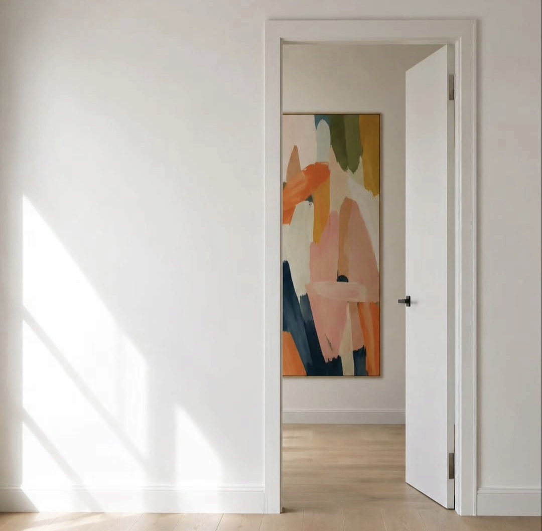Sunlit hallway with a colourful abstract painting framed through an open doorway