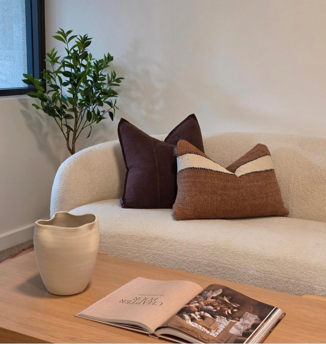Boucle sofa styled with textured cushions, a ceramic vase and a coffee table book